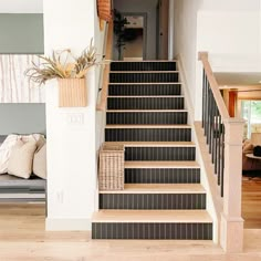 there is a basket on the stair case next to the carpeted stairs in this living room