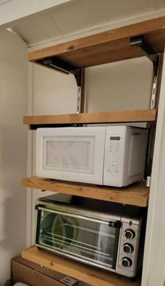 two microwaves are stacked on top of each other in the corner of a room