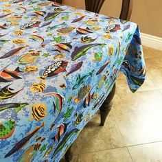 a blue table cloth with colorful fish and sea creatures on it is sitting in front of a chair