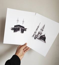 someone holding up two cards with an image of a mosque on them