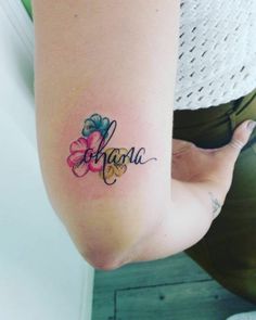 a woman with a tattoo on her arm that reads, ahoau and has flowers in it