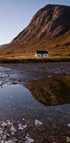 a small house sitting on top of a mountain next to a river