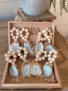 a wooden box filled with lots of white beads and seashells next to a potted plant