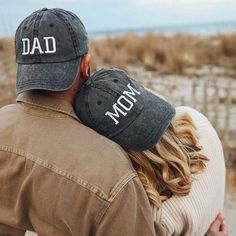 a man and woman hugging each other with the words dad on their caps over their heads