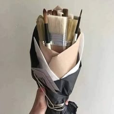 a person holding a bunch of paint brushes in their hand and wrapped in black paper