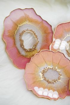 three pink and gold plates sitting on top of a white furnishing floor next to each other