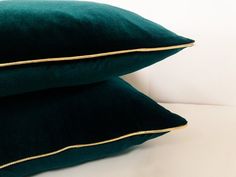 two dark green pillows with gold piping on the bottom and one black pillow top