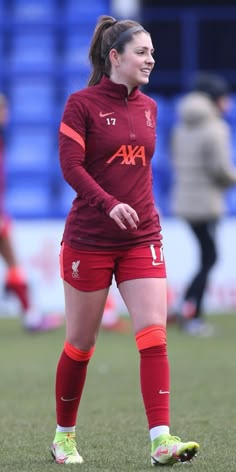 a female soccer player standing on the field with her foot in the air and smiling