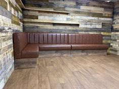 a brown leather couch sitting on top of a hard wood floor next to a wooden wall