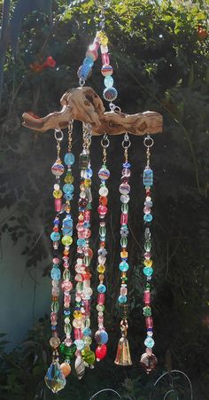 a wind chime hanging from a tree branch with beads and bells attached to it