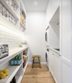 a laundry room with white shelving and wooden flooring