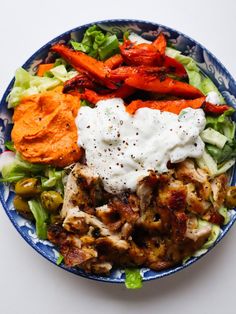 a blue and white plate topped with meat, veggies and sour cream sauce