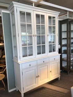 a white china cabinet with glass doors and drawers in the middle of a living room