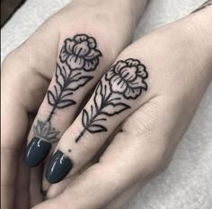 two hands with tattoos on them and one has a flower tattooed on the middle finger