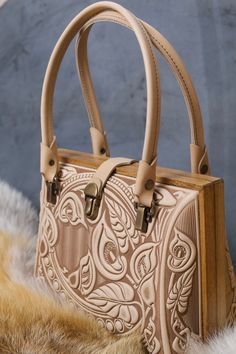 Model CALLA FLOWER Dimensions: 10.8/7.6/4.5" (27.5/19.5/11.5cm). Material: combination of genuine leather and real oak wood. This elegant "sack de voyage" made for special occasion and also for vintage style lovers. Combination of genuine leather and real oak wood making this bag very unique and attracting attention to beautiful owner. MADE IN LIMITED COLLECTION Thing to know: - Please double check your address and make sure it is correct prior to purchase! The shipping address CAN NOT be change Luxury Leather Engraved Shoulder Bag, Beige Embroidered Leather Bag, Unique Hand-tooled Brown Bag, Luxury Brown Hand Tooled Shoulder Bag, Luxury Vintage Hand Tooled Bag, Calla Flower, Elegant Purse, Material Combination, Minimal Wallet