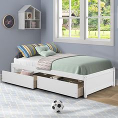 a white bed with drawers underneath it and a soccer ball on the floor next to it