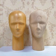 two wooden mannequin heads sitting next to each other