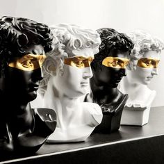 four white and black busturines with gold eye masks on top of a table