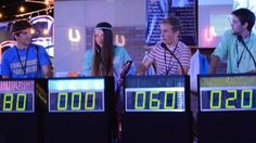 three people are standing in front of four electronic clocks with the numbers 00, 00 and 11 on them