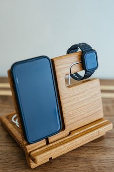 a cell phone is sitting on top of a wooden stand with an apple watch in it