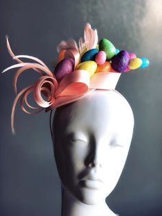 a white mannequin head wearing a pink hat with colorful candies on it