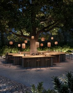 an outdoor dining area is lit up at night with paper lanterns hanging from the tree