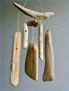 driftwood pieces hanging from strings in front of a gray wall