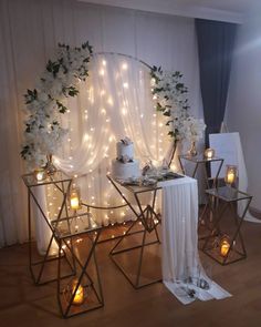 a table with candles and flowers on it in front of a white curtained backdrop