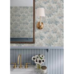 a bathroom sink sitting under a mirror next to a wall mounted faucet with flowers on it