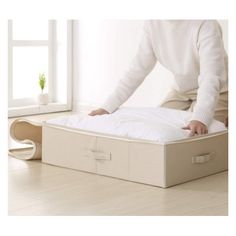 a person standing on top of a bed in a room with white walls and wooden floors