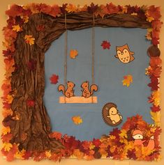 an autumn bulletin board with leaves, acorns and animals hanging from the branches