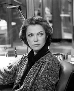 black and white photo of woman sitting in chair looking off to the side with eyes wide open