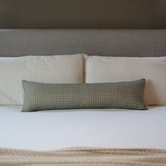 a bed with a white and green pillow on top of it