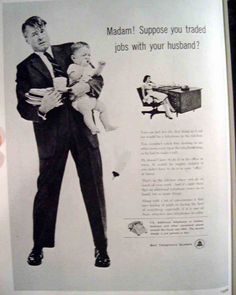 a man in a suit and tie holding a baby while standing next to an advertisement for jobs with your husband