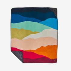 a multicolored blanket with mountains in the background on a white surface and black border