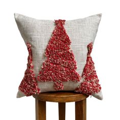 a red christmas tree pillow sitting on top of a wooden stool