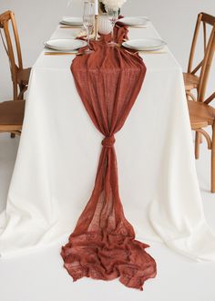 a white table topped with a vase filled with flowers next to a red cloth draped over it