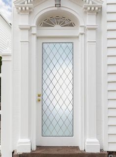 a white door with a glass window on the side of it and steps leading up to it