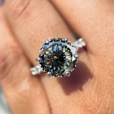 a woman's hand holding an engagement ring with a large diamond in the center