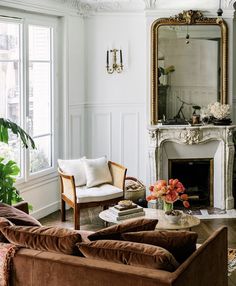 a living room filled with furniture and a fire place in front of a mirror on the wall