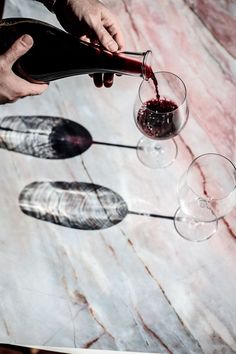 a person pouring wine into three glasses