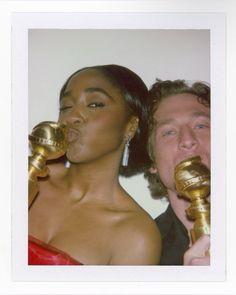 a man and woman holding golden objects in their mouths while standing next to each other