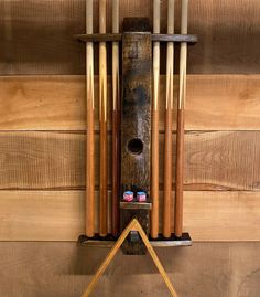 a wooden wall hanging with several pool cues on it