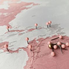 a map with pins stuck in the middle of it and some pink balls on top