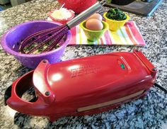 a red electric hand mixer sitting on top of a counter next to other kitchen items