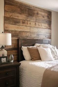 a bedroom with a wooden headboard on the wall and white bed linens in front of it