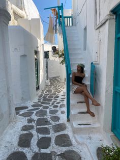 a woman sitting on the steps of an alleyway in oia, paros