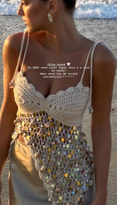 a woman standing on top of a beach next to the ocean wearing a white dress