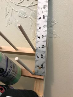 there is a tall ruler on the wall next to toothbrushes and other items