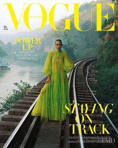 a woman in a long green dress on the cover of a magazine with train tracks